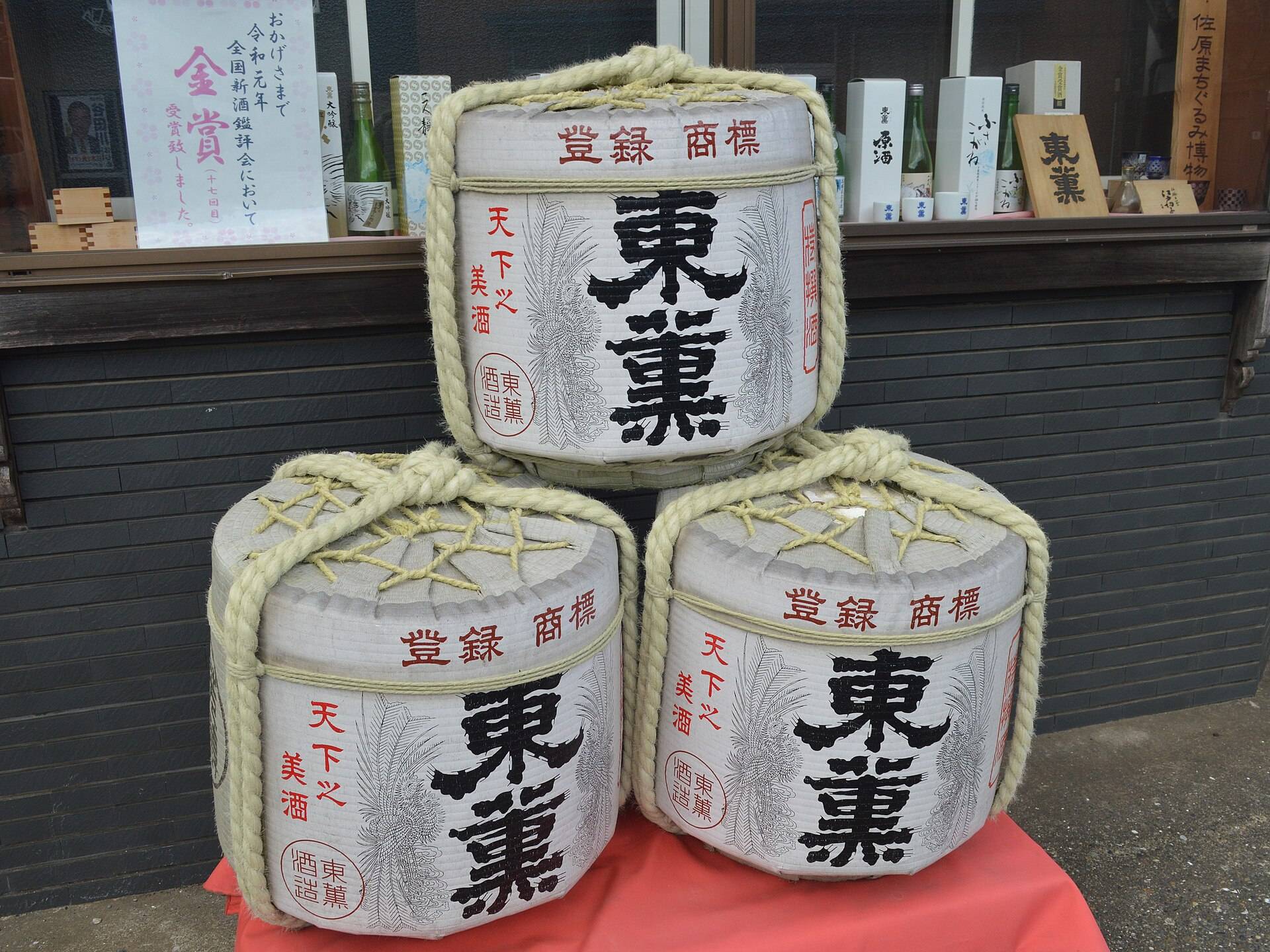 Straw-wrapped komodaru sake barrels stacked with bold brewery kanji on the front